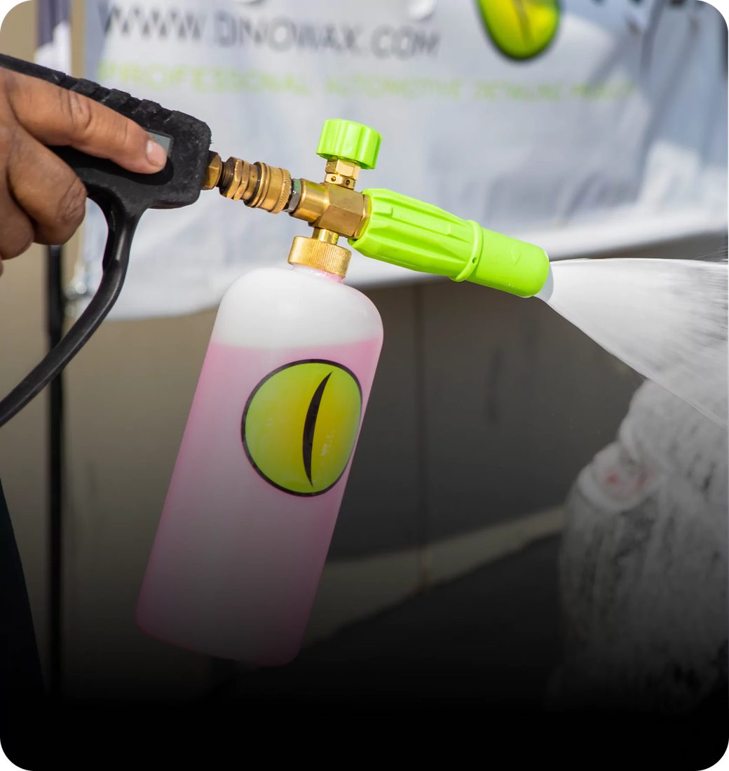 Person using a spray gun with a pink liquid bottle attached.