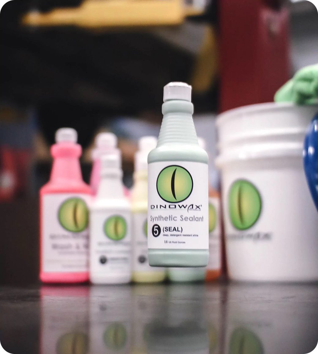Bottles of Dinowax products, including Synthetic Sealant, on a table.